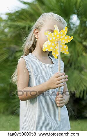 Girl holding pinwheel in front of face, portrait View Large Photo Image Stock Photo - Girl holding pinwheel in front of face, portrait. Fotosearch