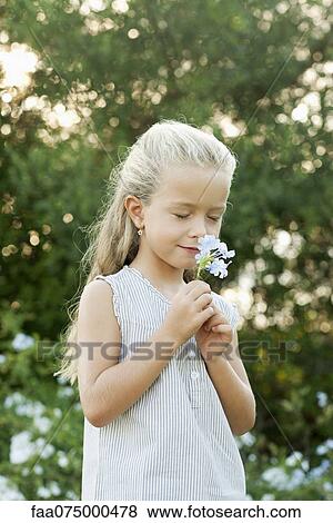 Stock Photo - Girl smelling flowers, eyes closed. Fotosearch