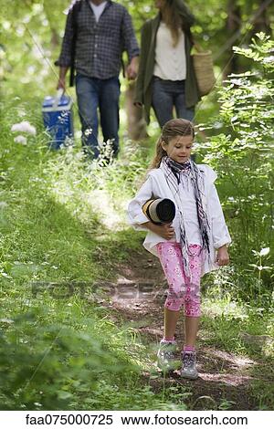Stock Photography - Girl walking in woods, parents in background. Fotosearch