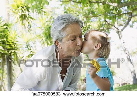 Stock Image - Little girl kissing grandmother on cheek. Fotosearch