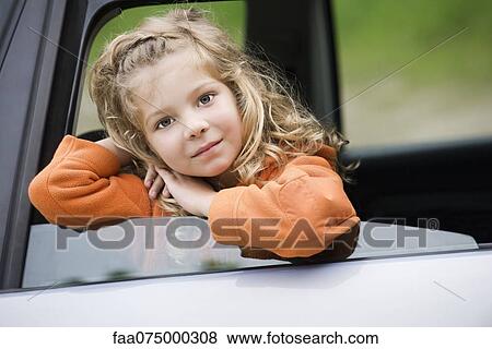 Stock Photo - Little girl looking out of car window, portrait. Fotosearch