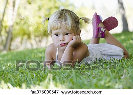 Little girl lying on grass, portrait View Large Photo Image Stock Photo - Little girl lying on grass, portrait. Fotosearch