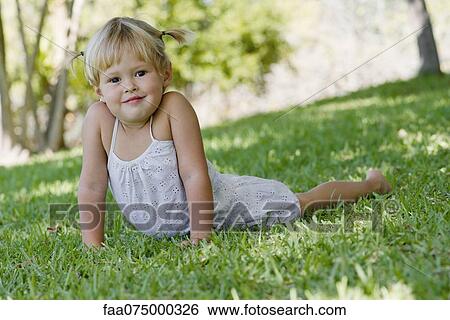 Little girl lying on grass, portrait View Large Photo Image Stock Photograph - Little girl lying on grass, portrait. Fotosearch