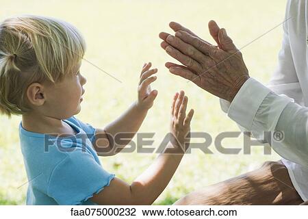 Stock Image - Little girl playing clapping game with grandmother, cropped. Fotosearch