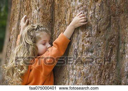 Little girl touching tree trunk View Large Photo Image Stock Image - Little girl touching tree trunk. Fotosearch