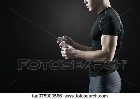Stock Photograph - Male athlete applying chalk to hands. Fotosearch