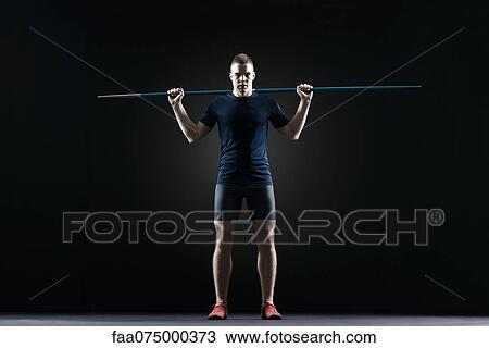 Stock Image - Male athlete standing with javelin. Fotosearch