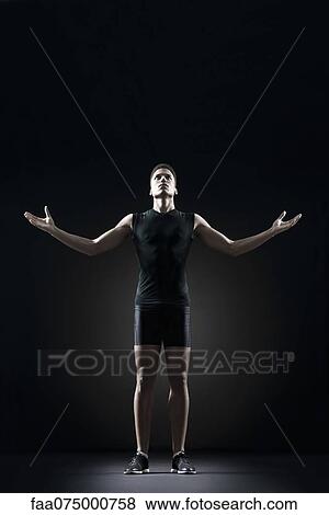 Stock Photo - Male athlete with arms outstretched, portrait. Fotosearch