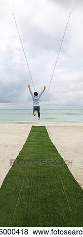 Man above artificial turf on beach, arms outstretched, rear view View Large Photo Image Stock Photo - Man above artificial turf on beach, arms outstretched, rear view. Fotosearch