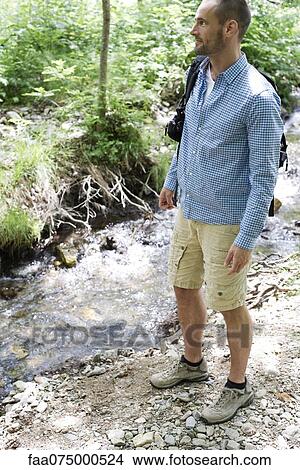 Picture - Man hiking along stream in woods. Fotosearch