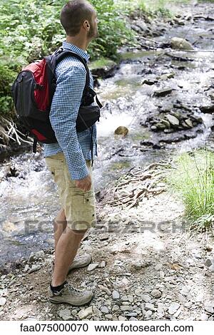 Man hiking along stream in woods View Large Photo Image Stock Image - Man hiking along stream in woods. Fotosearch