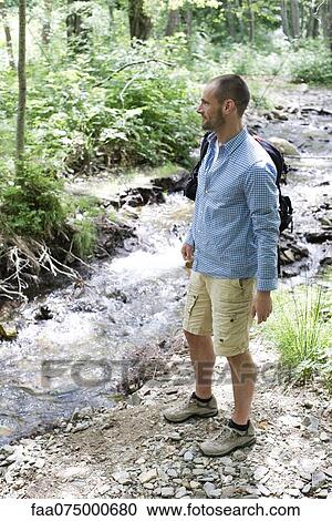 Man hiking along stream in woods View Large Photo Image Stock Image - Man hiking along stream in woods. Fotosearch