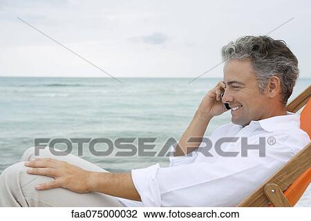 Man talking on cell phone at the beach View Large Photo Image Stock Image - Man talking on cell phone at the beach. Fotosearch