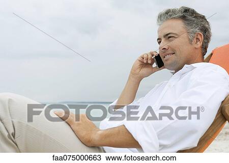 Man talking on cell phone at the beach View Large Photo Image Stock Image - Man talking on cell phone at the beach. Fotosearch