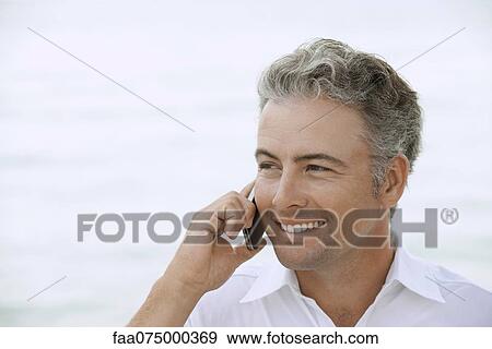Stock Photo - Man using cell phone outdoors, portrait. Fotosearch