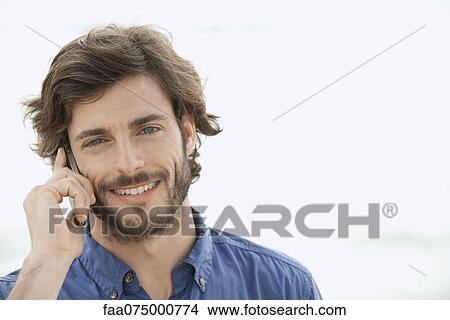 Man using cell phone outdoors, smiling, portrait View Large Photo Image Picture - Man using cell phone outdoors, smiling, portrait. Fotosearch