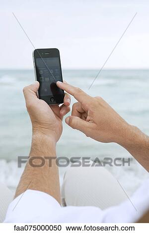 Man using smartphone at the beach, cropped View Large Photo Image Stock Image - Man using smartphone at the beach, cropped. Fotosearch