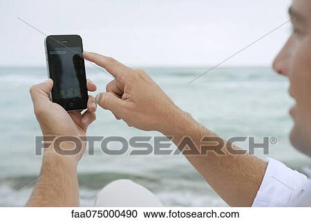 Man using smartphone at the beach View Large Photo Image Stock Image - Man using smartphone at the beach. Fotosearch