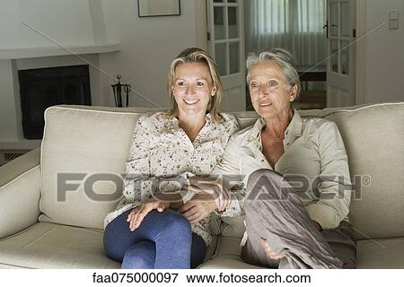 Mother and daughter watching TV in living room View Large Photo Image Stock Photo - Mother and daughter watching TV in living room. Fotosearch