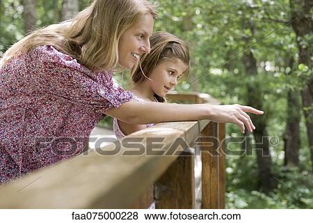 Stock Photo - Mother and young daughter looking over railing together. Fotosearch