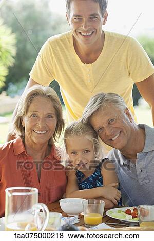 Multi-generation family at breakfast table outdoors, portrait View Large Photo Image Stock Photo - Multi-generation family at breakfast table outdoors, portrait. Fotosearch