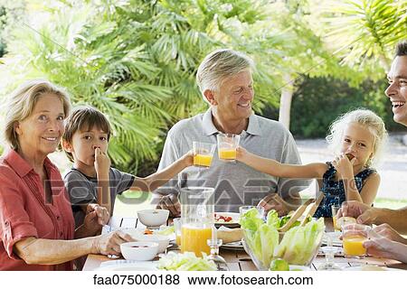 Multi-generation family enjoying meal outdoors View Large Photo Image Stock Photo - Multi-generation family enjoying meal outdoors. Fotosearch