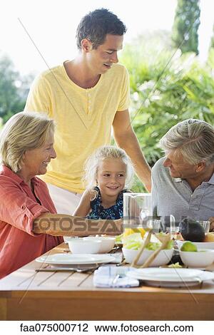 Stock Image - Multi-generation family having meal outdoors. Fotosearch