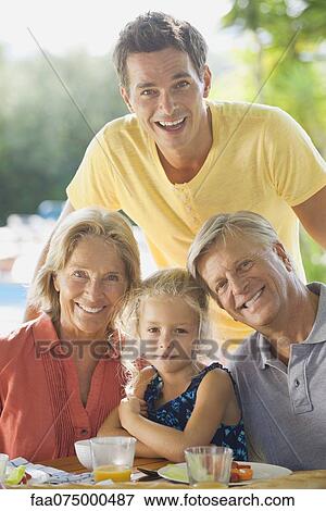 Stock Photo - Multi-generation family having meal outdoors, portrait. Fotosearch