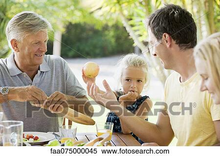 Stock Photography - Multi-generation family having meal outdoors. Fotosearch