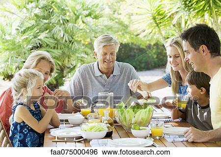 Stock Photograph - Multi-generation family having breakfast together outdoors. Fotosearch