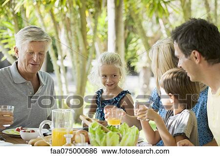 Multi-generation family having breakfast outdoors View Large Photo Image Stock Photograph - Multi-generation family having breakfast outdoors. Fotosearch