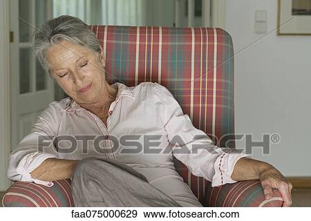 Stock Photo - Senior woman napping in armchair. Fotosearch