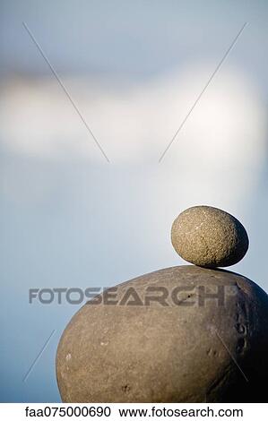Stock Image - Small stone stacked on top of larger stone. Fotosearch