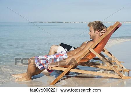 Two men sitting side by side on beach looking at ocean View Large Photo Image Stock Image - Two men sitting side by side on beach looking at ocean. Fotosearch