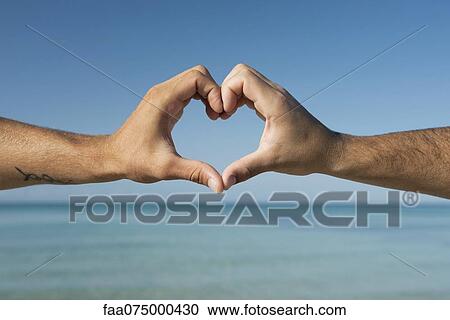 Two men's hands forming heart shape by ocean, cropped View Large Photo Image Stock Image - Two men's hands forming heart shape by ocean, cropped. Fotosearch