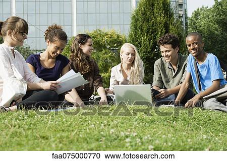 Stock Image - University students studying on grass outdoors, low angle view. Fotosearch