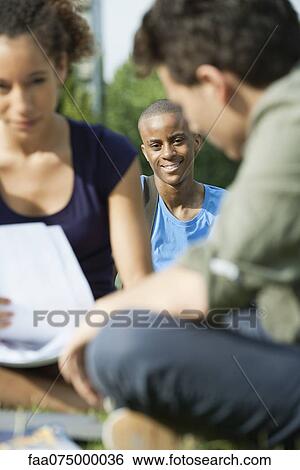 University students studying outdoors, focus on one man in background View Large Photo Image Stock Photograph - University students studying outdoors, focus on one man in background. Fotosearch