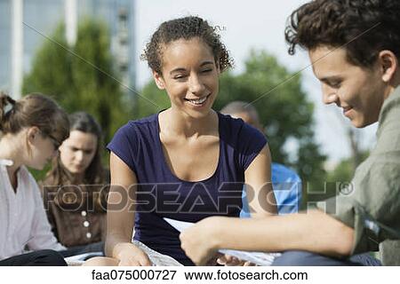 Stock Photo - University students studying together outdoors, focus on one woman. Fotosearch