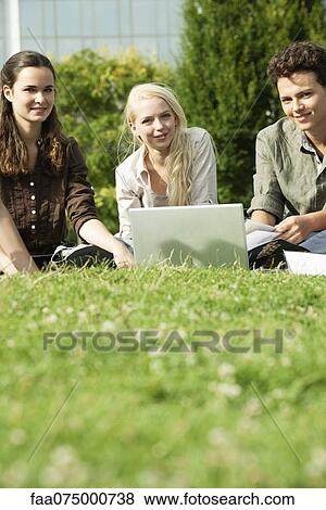 Stock Photo - University students studying together on grass, low angle view. Fotosearch