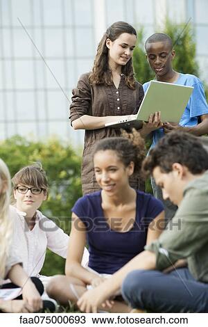 University students using laptop computer outdoors, focus on people in background View Large Photo Image Stock Image - University students using laptop computer outdoors, focus on people in background. Fotosearch