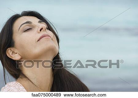 Woman breathing outdoors with head back and eyes closed View Large Photo Image Stock Photo - Woman breathing outdoors with head back and eyes closed. Fotosearch