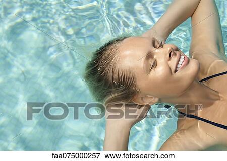 Woman floating in pool with eyes closed View Large Photo Image Stock Photo - Woman floating in pool with eyes closed. Fotosearch