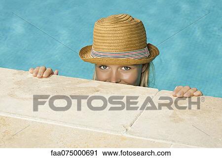 Stock Image - Woman in pool, peeking over edge at camera. Fotosearch