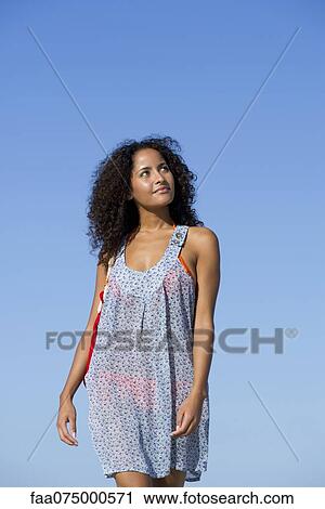 Woman in sundress walking outdoors, looking up and smiling View Large Photo Image Stock Image - Woman in sundress walking outdoors, looking up and smiling. Fotosearch