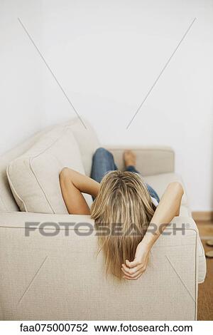 Stock Image - Woman lying on sofa, rear view. Fotosearch