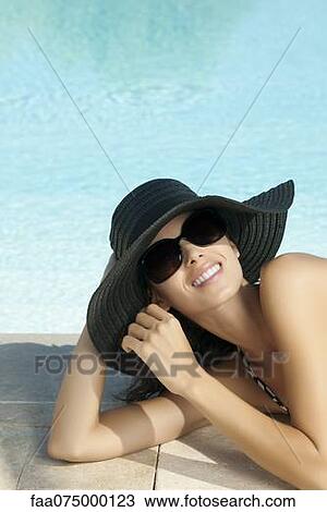 Woman relaxing by pool, wearing sun hat, portrait View Large Photo Image Stock Image - Woman relaxing by pool, wearing sun hat, portrait. Fotosearch