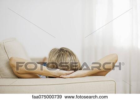 Stock Photo - Woman resting on sofa, rear view. Fotosearch