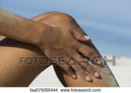 Woman rubbing sand off legs at the beach, cropped View Large Photo Image Picture - Woman rubbing sand off legs at the beach, cropped. Fotosearch