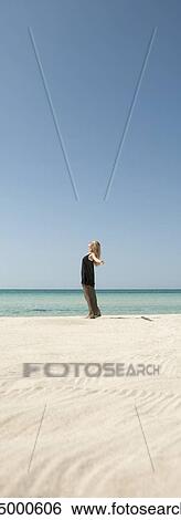 Woman standing on beach with arms out, side view View Large Photo Image Stock Photograph - Woman standing on beach with arms out, side view. Fotosearch