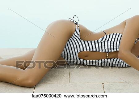 Stock Image - Woman sunbathing beside pool, cropped. Fotosearch
